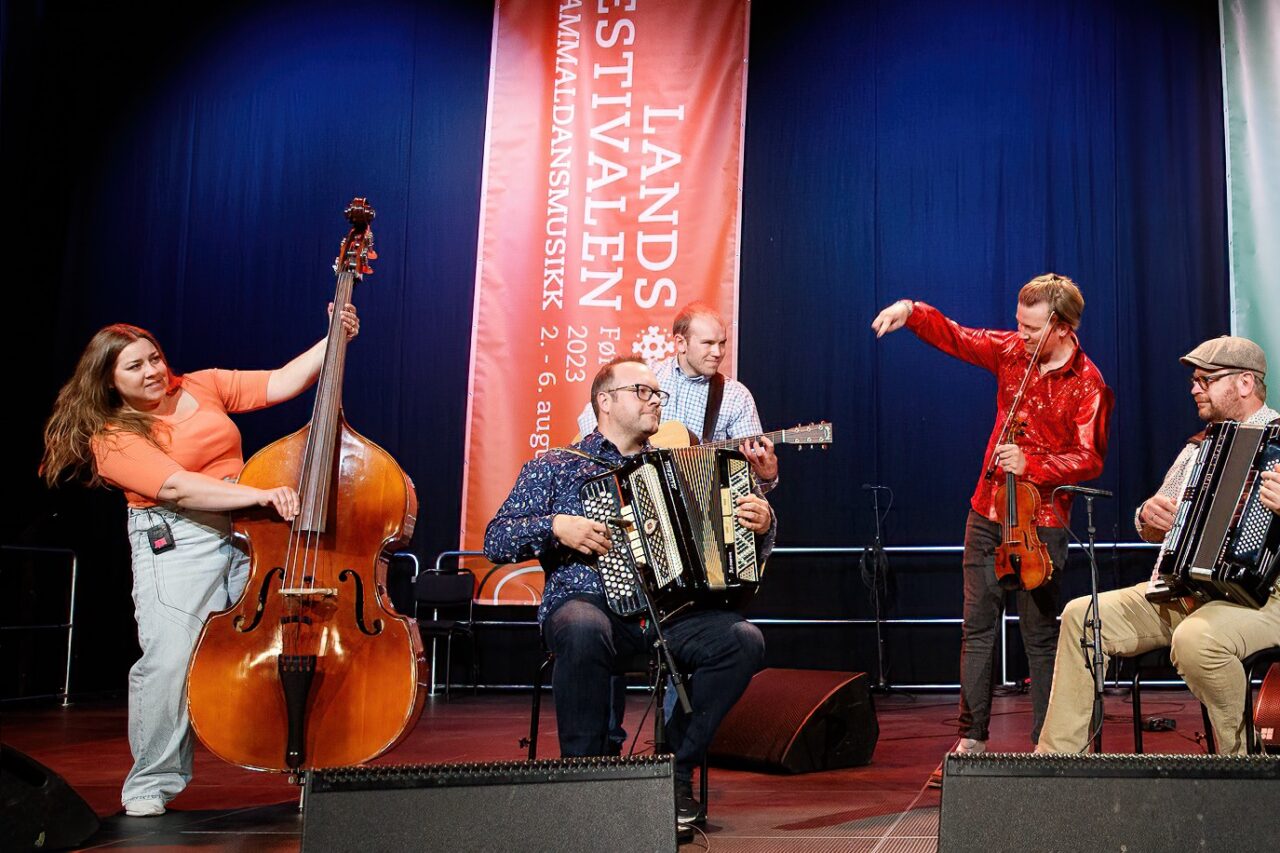 Band med fem musikere, to på trekkspill, en fele, en kontrabass, en gitar. Kvinne på kontrabass, menn på de andre instrumentene. Bandet spiller på en scene under Landskappleiken 2023