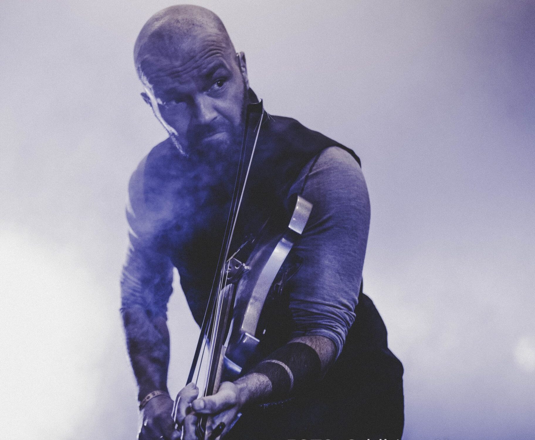 Nærbilde av mann, overkropp og hode, som spiller fele på scene i lilla lys