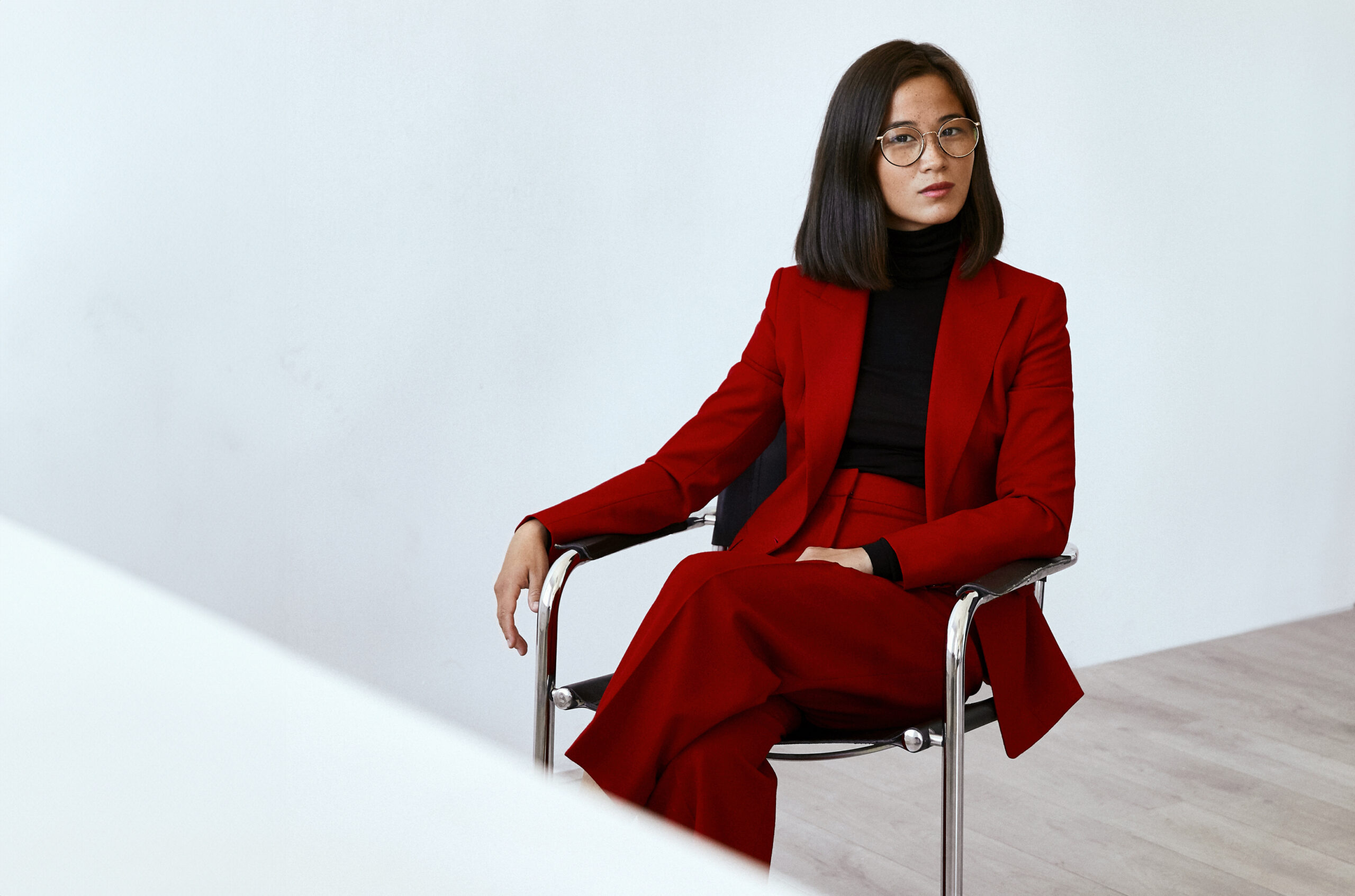 Foto av den norske komponisten Anna Berg, sittende med rød jakke mot hvit bakgrunn